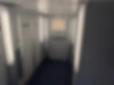 A lower-deck corridor lined with lavatories on both sides, lit by tall vertical light panels