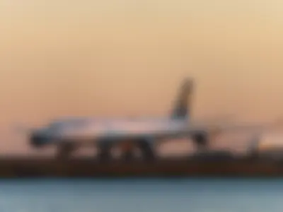 Lufthansa A340-600 taxiing head-on along the taxiway, glowing in the orange sunset light, with a Delta regional jet behind it